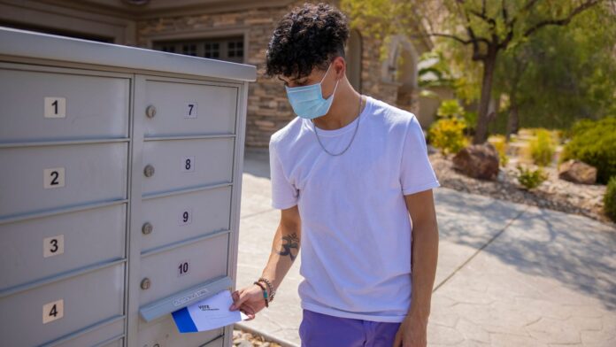 Un hombre joven pone su boleta electoral en el correo