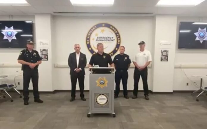 El sheriff Robert Norris ofrece declaraciones junto a autoridades locales y equipos de emergencia durante una rueda de prensa transmitida por la Oficina de Manejo de Emergencias del Condado de Kootenai, tras la emboscada contra bomberos en Canfield Mountain. Captura de pantalla