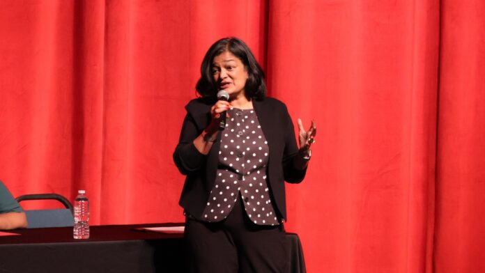 La congresista Pramila Jayapal habla sobre abusos contra inmigrantes durante el Town Hall en Spokane, el 30 de junio de 2025. © Latino Herald Pramila Jayapal hablando con micrófono en mano durante el Town Hall en Spokane frente a un telón rojo. © Latino Herald