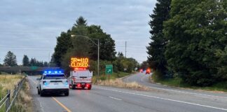 Dos personas mueren en choque frontal causado por conductor ebrio en SR 410 Vehículos de emergencia bloquean la SR 410 oeste tras un accidente fatal, con un letrero luminoso que indica el cierre total de la vía.