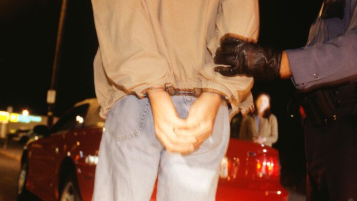 Teenage boy (16-17) being arrested, mid section