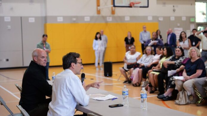 1 El gobernador Bob Ferguson y el congresista Rick Larsen conversan con familias y representantes de la comunidad en un Town Hall celebrado en Lynnwood Elementary School, discutiendo el impacto de los recortes a SNAP. (Foto cortesía de la oficina del gobernador de Washington, 08/21/2025)