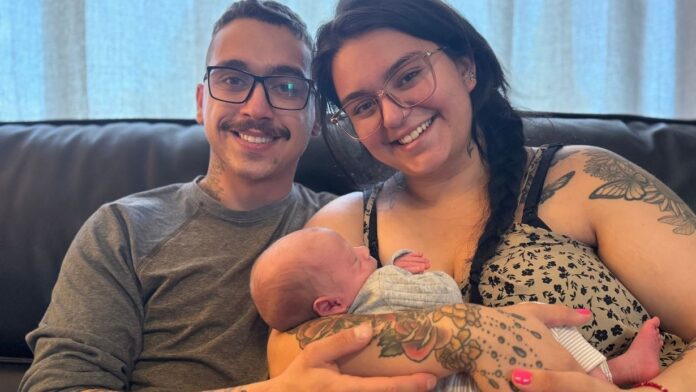 Georgia y Chris Rocca-Vázquez, padres del recién nacido, Lucas, sonríen a la cámara mientras sostienen a su bebé.