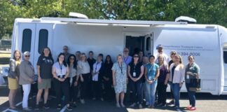 Condado de Snohomish lanza innovadora clínica móvil para tratar la adicción a opioides Foto: Funcionarios electos locales y estatales, personal del Departamento de Salud y Servicios Humanos del condado de Snohomish y personal de la clínica del Centro de Tratamiento Integral de Lynnwood posan frente a la nueva clínica móvil - Cortesía del condado de Snohomish