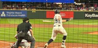 Los Marineros aseguran su pase a los playoffs y se acercan al título divisional Un jugador de béisbol con un uniforme crema y rayas azules conecta un hit. Se ve desde atrás al catcher en cuclillas y al umpire gritando la jugada.