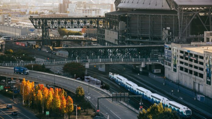 Tren Sounder junto a los estadios Un tren Sounder pasa junto a los estadios Lumen Field y T-Mobile en Seattle. Es otoño y muestra la calle 4ta al frente