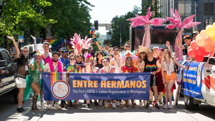 Entre Hermanos desfile Pride Alt Text: Miembros de la organización Entre Hermanos participan en el desfile del Orgullo en Seattle con un colorido contingente Latin LGBTQ+