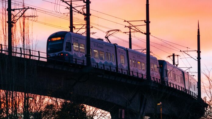 Light Rail Extension Tren ligero de Sound Transit en Seattle cruzando un viaducto bajo un cielo rosado al atardecer