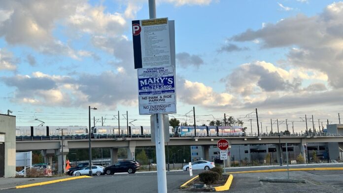 2 etrero de estacionamiento privado con advertencia de remolque en lote frente a la estación de tren ligero Lynnwood City Center.