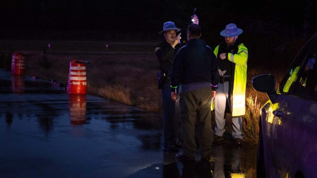 Oficiales realizan una prueba de sobriedad en carretera a un conductor, utilizando una linterna como parte del examen