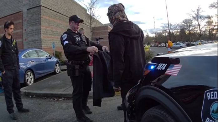 Foto: Agentes de Redmond le entregan a un hombre en situación de calle una chamarra - Cortesía de la policía de Redmond