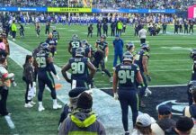 Seahawks derrotan a los Rams y avanzan al Super Bowl LX Seattle Seahawks realizando ejercicios de calentamiento en la línea lateral del campo en el estadio Lumen Field antes del partido contra Los Angeles Rams, rodeados de aficionados y personal del equipo.