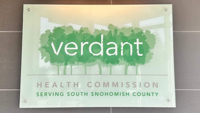 Letrero de la Verdant Health Commission con fondo verde y siluetas de árboles en su sede del sur de Snohomish County