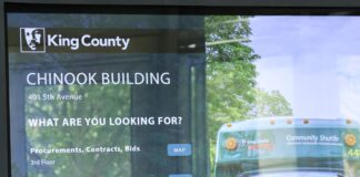 El condado King comenzará a aplicar el mandato de regreso a la oficina Pantalla informativa en el lobby del edificio Chinook de King County que muestra servicios y ubicación de oficinas.