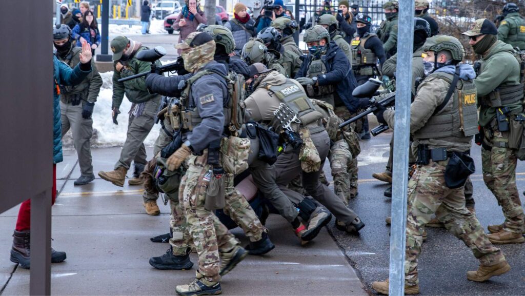 Agentes de ICE repelen una manifestación frente al edificio Bishop Henry Whipple, en St. Paul, Minnesota, en enero de 2026. En este complejo operan las cortes migratorias a las que ICE traslada a personas detenidas - Imagen capturada por Colton de Blue G Productions.