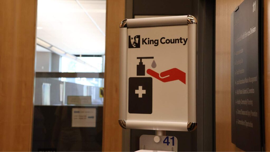 Logo de King County con ícono de desinfectante de manos ubicado en un pasillo interior del edificio Chinook en el centro de Seattle.