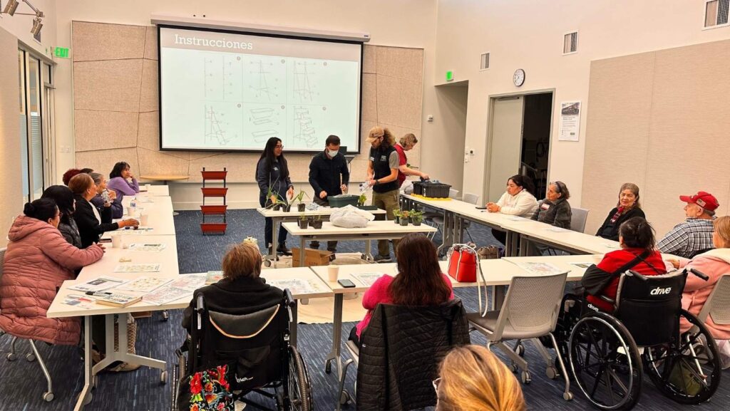 Grupo de personas mayores participando en un taller comunitario en Verdant, con instructores demostrando técnicas de jardinería