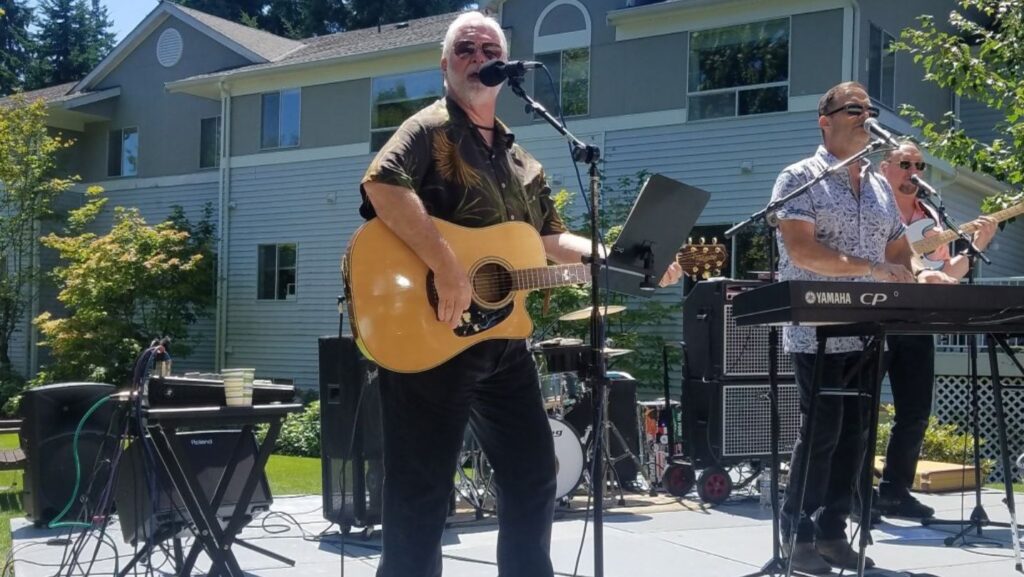 Foto: Jim Smith amenizó la exhibición anual de autos de Fairwinds Brighton Court como vocalista principal de la banda GenRASun, – Cortesía del Lynnwood Times