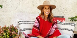 Sylvia Villagrán: la voz latina detrás de grandes eventos internacionales Sylvia Villagrán sentada al aire libre con sombrero y poncho rojo, sonriendo en un entorno relajado.