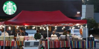 Negocios con licencia reportan pérdidas: WA va contra puestos de comida sin permiso Puesto de comida instalado en una acera frente a Highway 99 en Lynnwood, Washington, con vendedores y clientes bajo una carpa roja durante la noche.