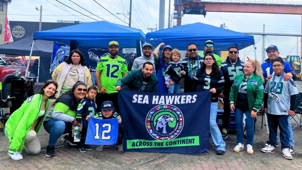 Miembros del club Sea Hawkers Latin America en evento de tailgate con el banner oficial que dice Across the Continent