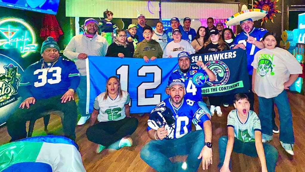 Aficionados de Sea Hawkers Latin America celebran en restaurante con bandera del número 12 y banner del club oficial