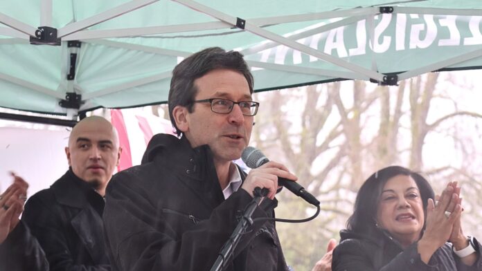 El gobernador Bob Ferguson pronuncia un discurso en las escalinatas del Capitolio durante el Día Legislativo Latino en Olympia, acompañado por la representante Lilian Ortiz-Self. 02/02/26. Foto: Latino Herald TM.