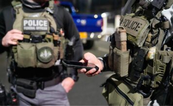 CNN: Trump prepara más operativos de ICE en lugares de trabajo para aumentar arrestos Dos agentes con equipo táctico y chalecos que dicen “Police” y “Federal Officer” durante un operativo nocturno.