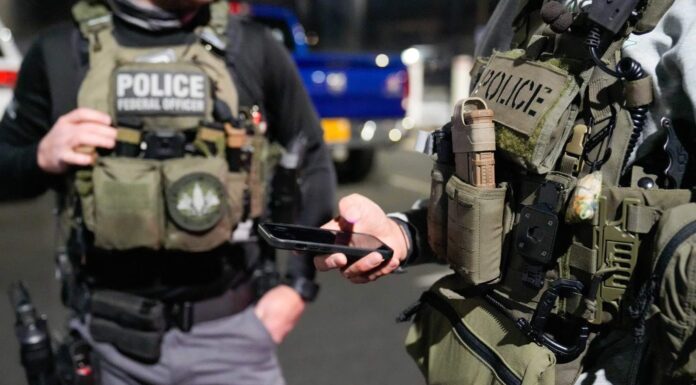 CNN: Trump prepara más operativos de ICE en lugares de trabajo para aumentar arrestos Dos agentes con equipo táctico y chalecos que dicen “Police” y “Federal Officer” durante un operativo nocturno.