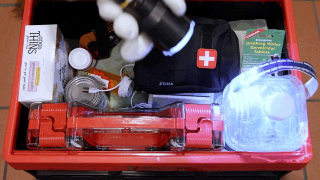 Caja de kit de emergencia con linterna, comida, agua y botiquín de primeros auxilios.