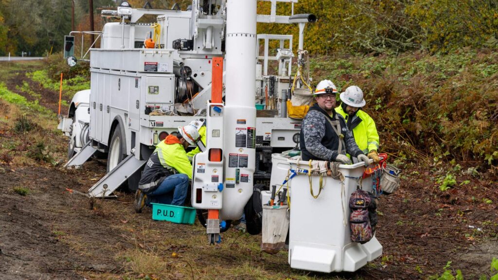 Trabajadores del Snohomish PUD realizando labores de mantenimiento eléctrico con camión especializado.