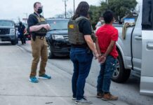 Tribunal rechaza política de detención obligatoria de ICE Agentes de HSI detienen a un hombre esposado junto a una camioneta blanca durante un operativo en la calle.