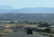 Demandan a empresa agrícola de Yakima por visas de trabajadores temporales Carretera atravesando el valle de Yakima, con vista a zonas agrícolas y montañas al fondo, en un día despejado.