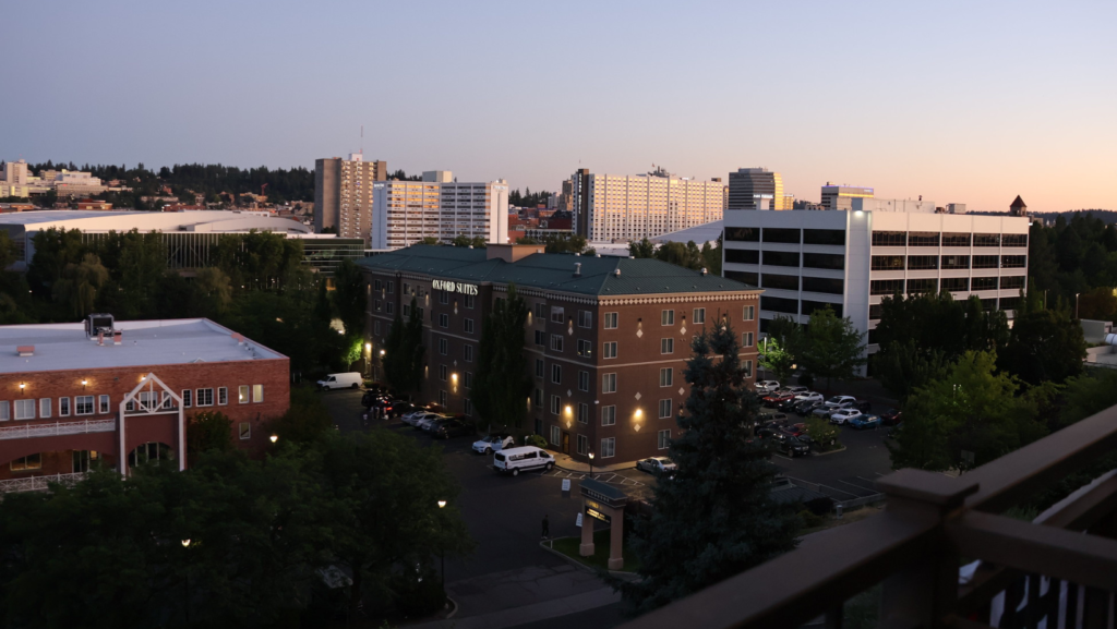 Vista urbana de Spokane, Washington, al atardecer con edificios residenciales y comerciales, estacionamientos y árboles en primer plano
