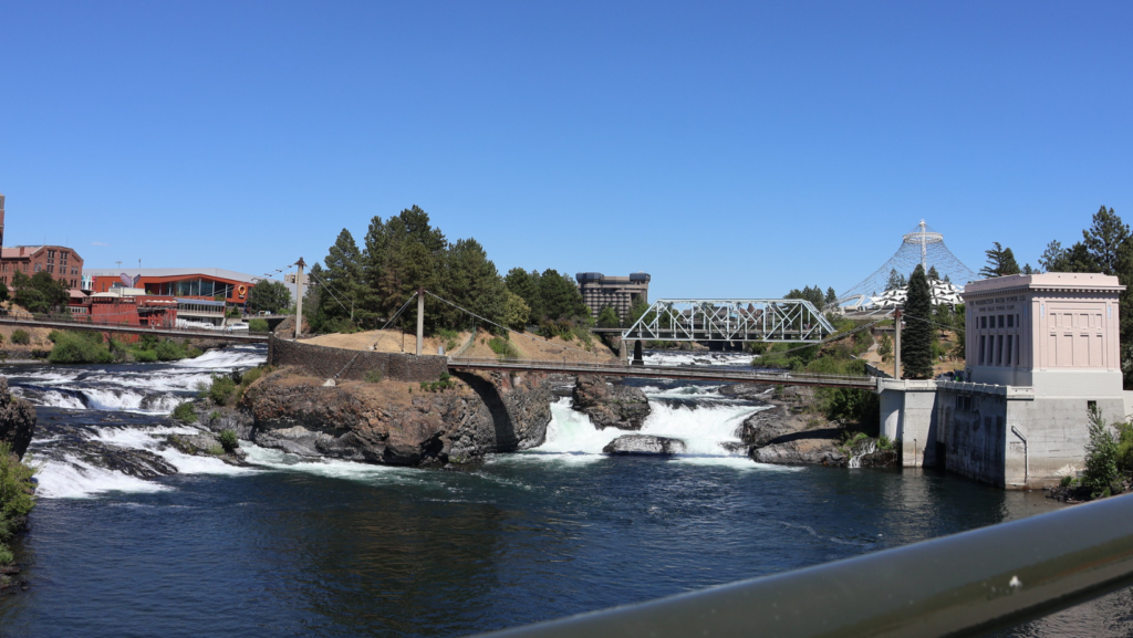 Cataratas del río Spokane con puentes y edificios cercanos, incluyendo una estructura histórica y pasarelas sobre el agua en Spokane, Washington.