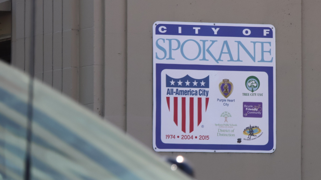 Señal oficial de “City of Spokane” en una pared, con emblemas como All-America City y otros reconocimientos de la ciudad.