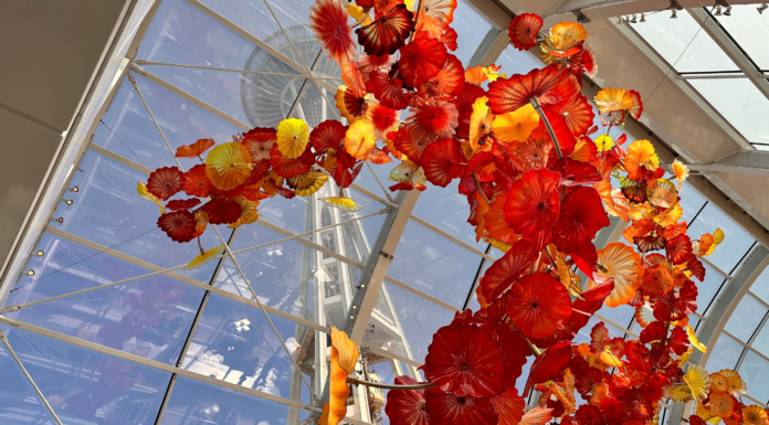 Imponen fianza de $100,000 al hombre acusado de vandalizar el Chihuly Garden and Glass Arte en vidrio soplado con formas florales en tonos rojos, naranjas y amarillos suspendida en el techo de un invernadero con estructura de vidrio en Chihuly Garden and Glass.