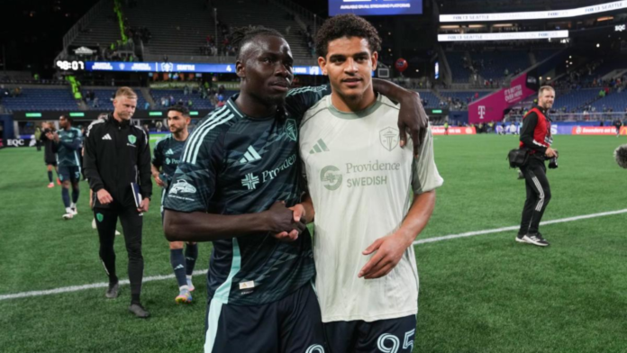 De izquierda a derecha, se observa a Georgi Minoungou junto a Osaze De Rosario después de un partido — Foto: Sounders FC Communications