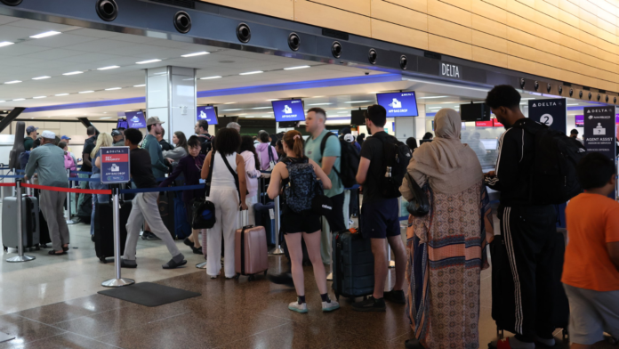 Pasajeros hacen fila en el área de check-in de Delta en el Aeropuerto Internacional de Seattle-Tacoma, con equipaje de mano y maletas.