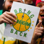 La NBA da luz verde a la expansión y apunta a Seattle y Las Vegas Aficionados alzan un letrero pidiendo el regreso de los Seattle SuperSonics, reflejo de una afición que aún no olvida a su equipo, durante un partido de baloncesto universitario en Seattle, en diciembre de 2023. (Foto AP/Lindsey Wasson)