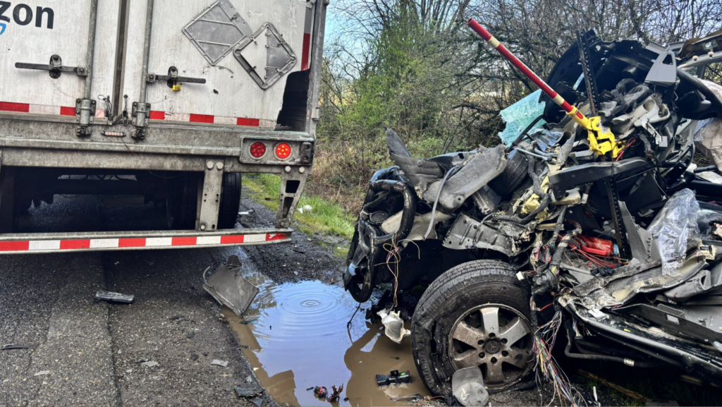 Vehículo severamente dañado tras un choque en la autopista I-5, donde una furgoneta de transporte impactó contra un camión en el carril sur en el condado de Thurston.