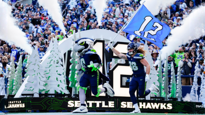 Blitz, la mascota de los Seahawks, y el ala cerrada Brady Russell (38) saltan al campo antes del partido contra los Rams de Los Ángeles, el domingo 3 de noviembre de 2024 en Seattle. (Foto AP/Ben VanHouten)