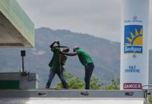 Haitianos recortan la ya escasa comida y se preguntan cómo sobrevivirán al alza del combustible Trabajadores manipulan equipo en una estación de combustible con un tanque de gas propano al fondo, en medio de un entorno montañoso en Haití.