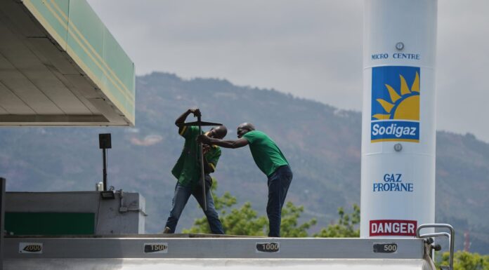 Haitianos recortan la ya escasa comida y se preguntan cómo sobrevivirán al alza del combustible Trabajadores manipulan equipo en una estación de combustible con un tanque de gas propano al fondo, en medio de un entorno montañoso en Haití.