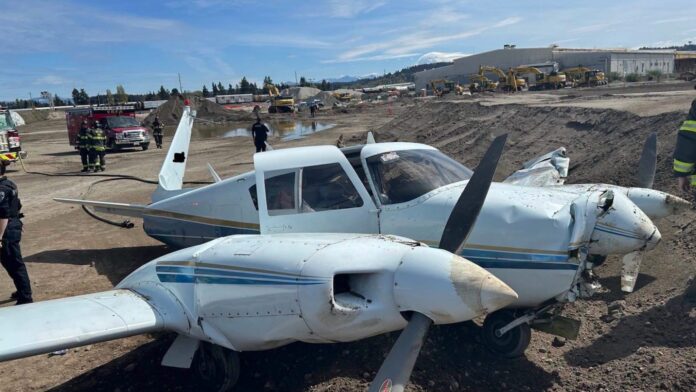 Avioneta bimotor dañada tras un aterrizaje de emergencia en un sitio de construcción en Auburn, Washington, mientras equipos de emergencia aseguran el área.