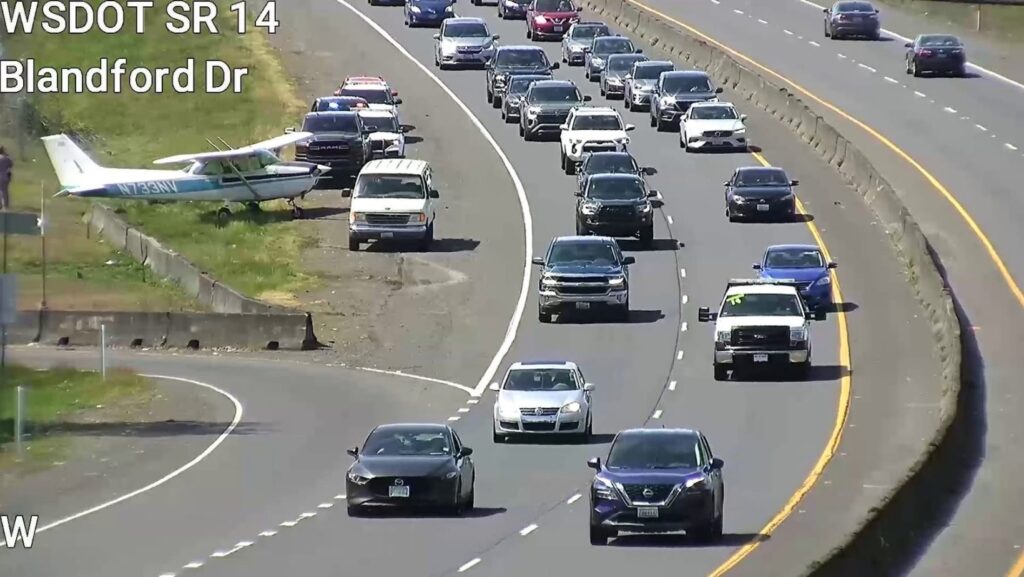Avioneta estacionada al costado de la SR 14 con vehículos circulando lentamente en Vancouver, Washington.