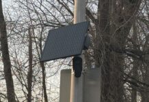 Washington refuerza regulación de cámaras Flock y protege datos de conductores Cámara de seguridad Flock con panel solar instalada en un poste en Renton, rodeada de árboles.