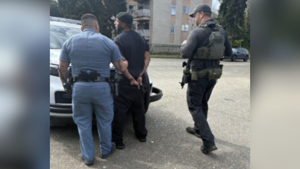 Agentes de la Patrulla Estatal de Washington (WSP) arrestan a un hombre con las manos esposadas detrás de la espalda junto a un vehículo en West Seattle.