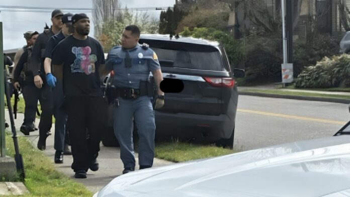 Agentes de la Patrulla Estatal de Washington escoltan a un hombre arrestado por una calle de West Seattle durante un operativo policial.