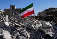 Trump sentencia a Irán: “toda una civilización morirá esta noche” Una bandera iraní ondea entre los escombros de una estación de policía destruida tras los bombardeos de Estados Unidos e Israel en Teherán, Irán, en marzo de 2026 (Foto de AP/Vahid Salemi)